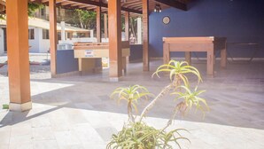 Un espace extérieur aménagé en terrasse, avec des pergolas en bois, une table et des plantes en pot.