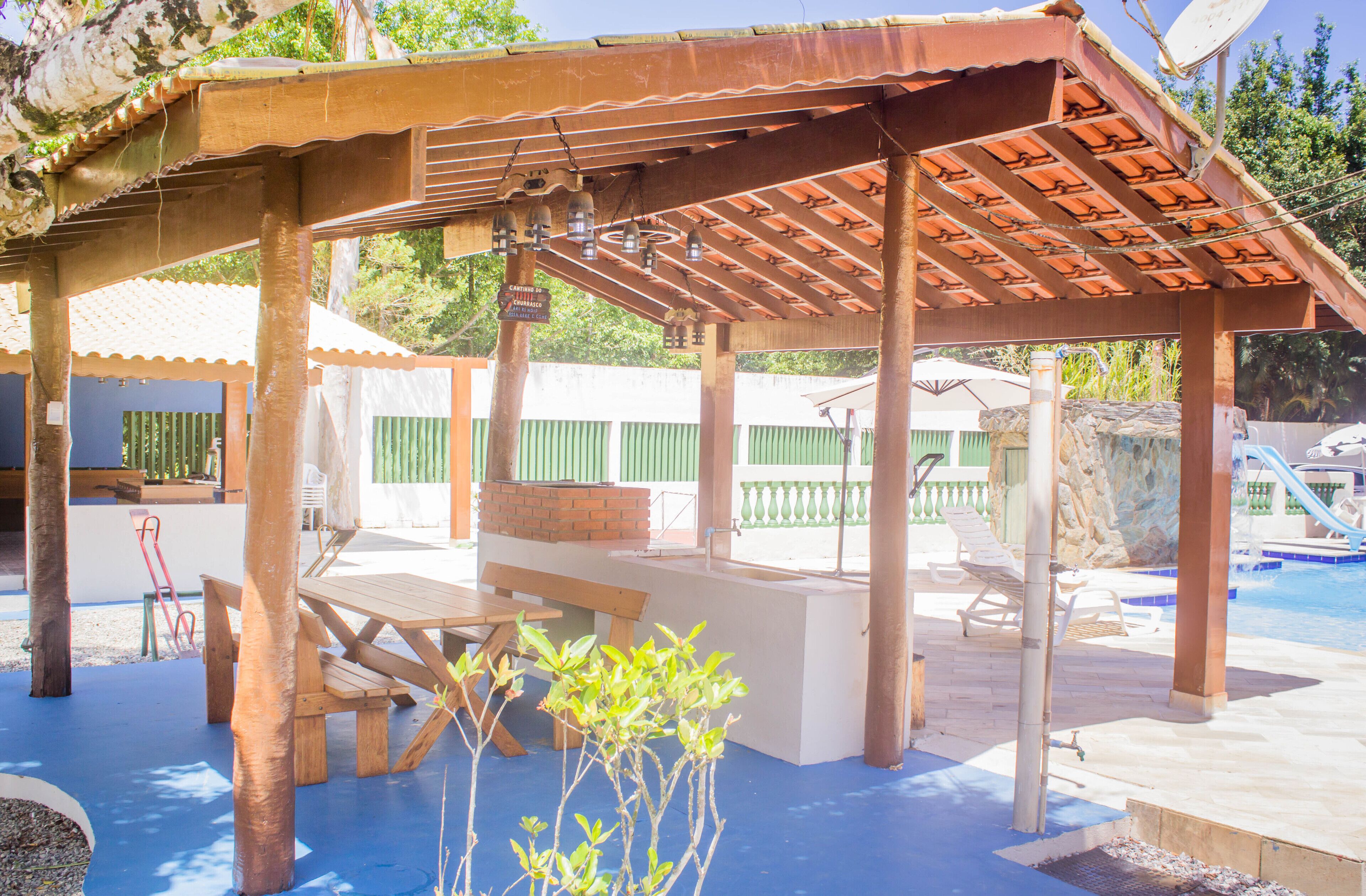A covered patio area with a pool, wooden benches, and a table.