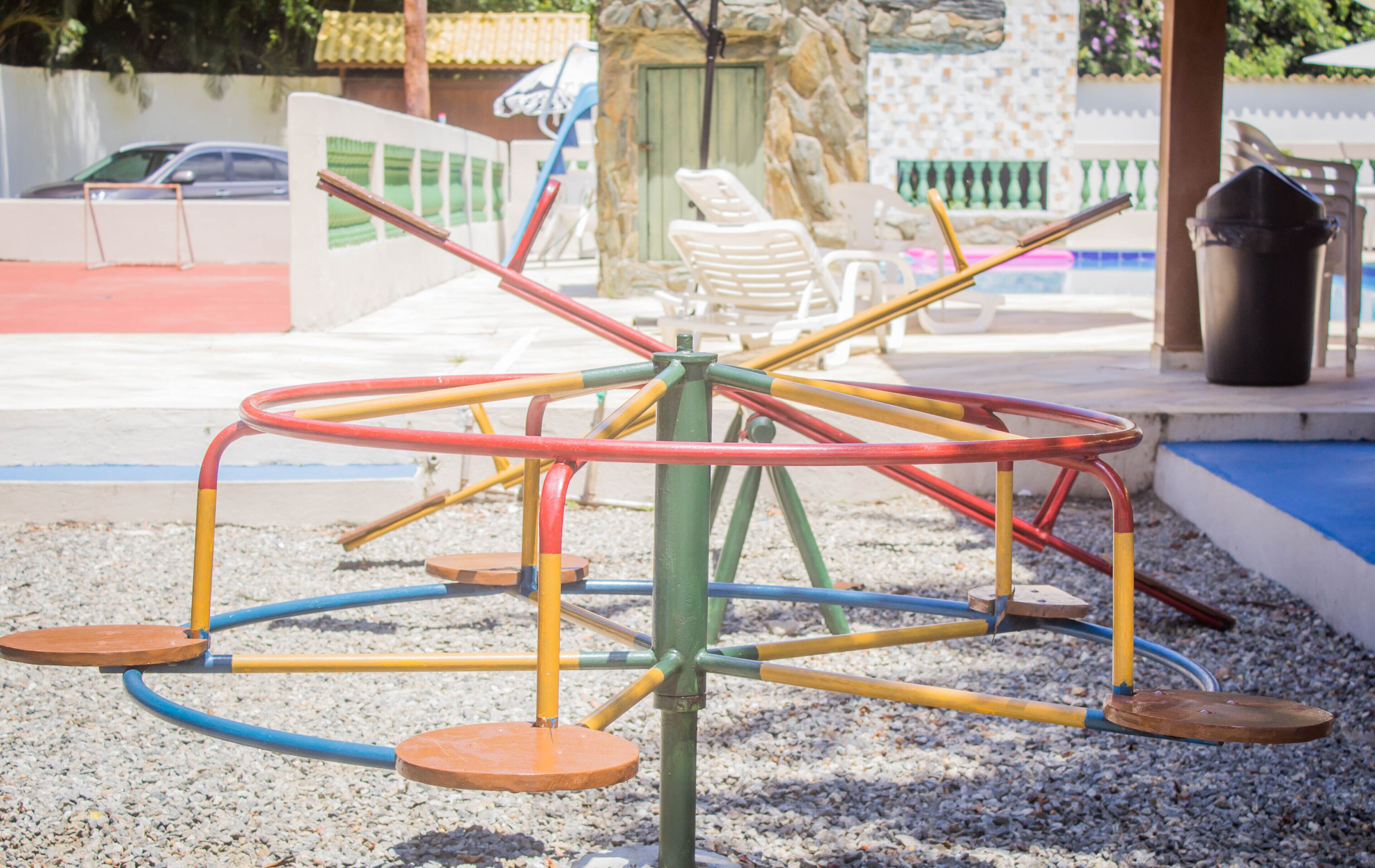 Un parque infantil con un carrusel de colores y una piscina pequeña al fondo.