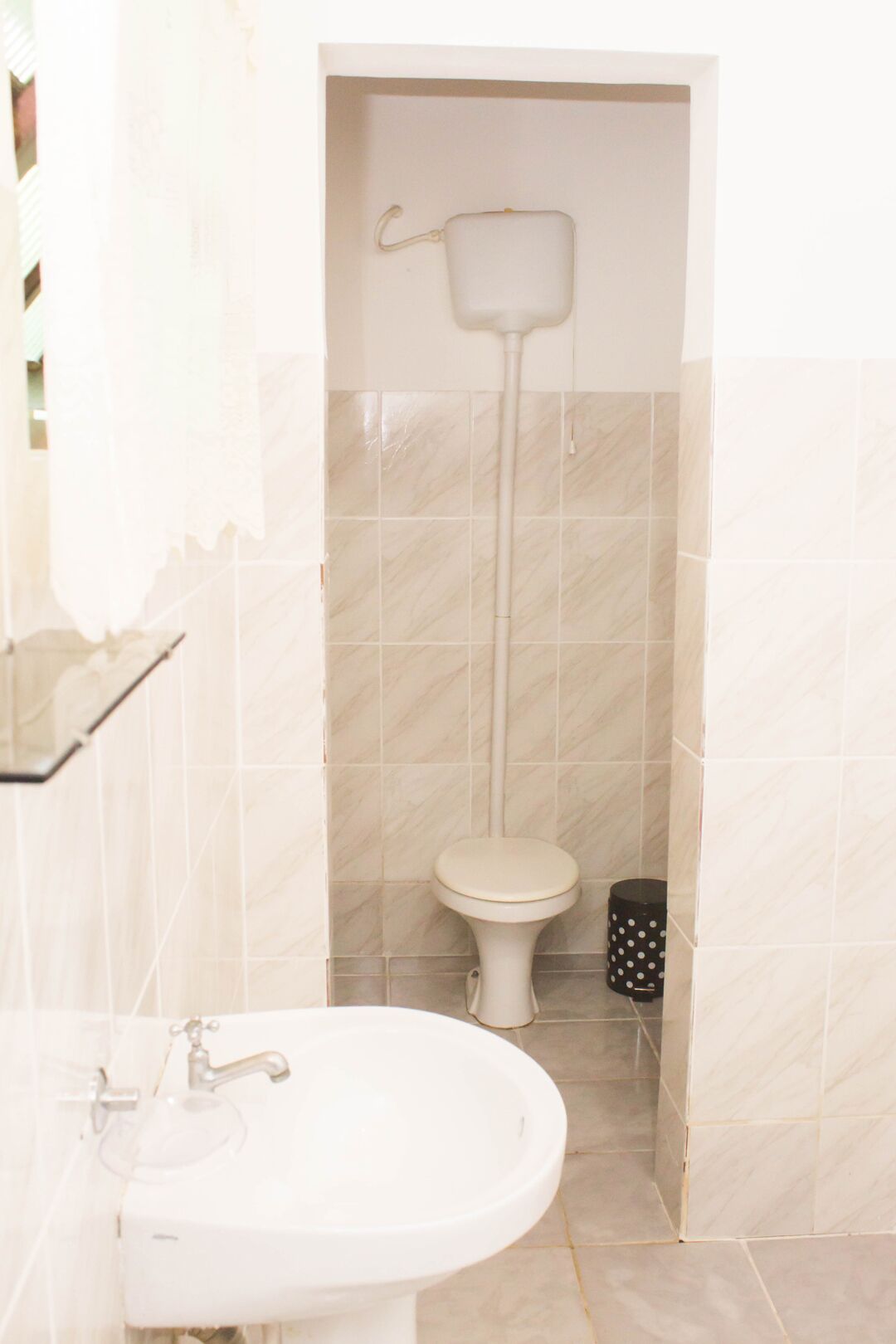 Un baño con inodoro, lavamanos y dispensador de papel higiénico.