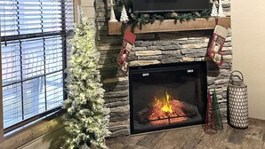 A fireplace with a TV above it, a Christmas tree, and a stone wall.