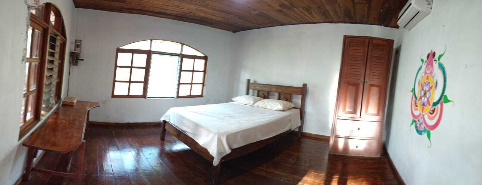 A bedroom with a wooden bed, a window, and a door.