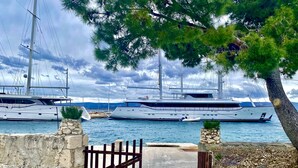 Un port de plaisance où sont amarrés des yachts, une porte en pierre et un sentier menant à l’eau.