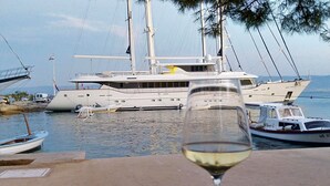 Un verre de vin blanc, avec vue sur un yacht amarré dans une marina.