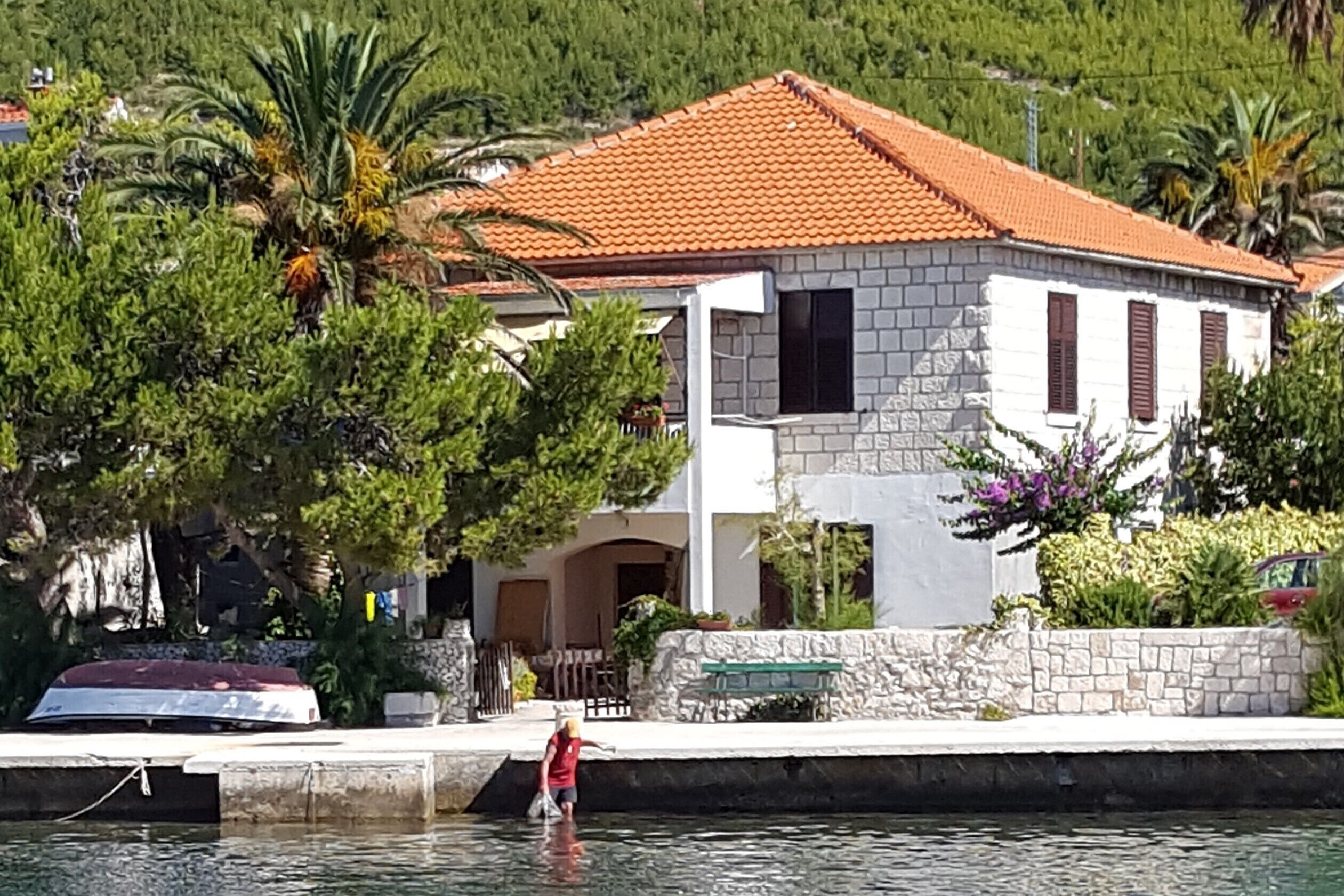 Uma casa com telhado de telhas vermelhas, paredes de pedra e uma escadaria de pedra que leva à entrada.