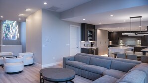 Ein modernes Wohnzimmer mit einem grauen Ecksofa, einem Glastisch und weißen Sessel.