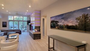 Ein modernes Wohnzimmer mit Kamin, einem großen Gemälde von Sternennacht und einem Glastisch.
