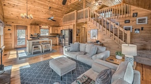 A log cabin interior with a living room, kitchen, and a staircase leading to an upper level. - Copper Ridge Hideaway - Dog Friendly | Pac Man Arcade Game | Hot Tub (Mineral Bluff)