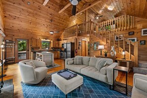 A spacious cabin interior with a kitchen, dining area, and a loft bedroom.
