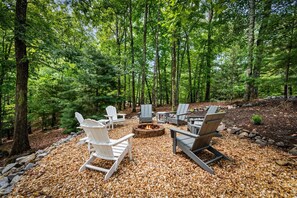 A forest setting with outdoor seating and a fire pit.