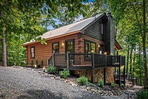 A cabin with a wooden exterior, a balcony, and a stone foundation. - Copper Ridge Hideaway - Dog Friendly | Pac Man Arcade Game | Hot Tub (Mineral Bluff)