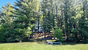 A cabin surrounded by tall trees, a dock, and a bench. - Waterfront Paradise! Boat available for rent. (Waupaca)