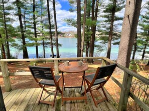 A wooden deck with two chairs and a table, overlooking a lake surrounded by trees. - Waterfront Paradise! Boat available for rent. (Waupaca)
