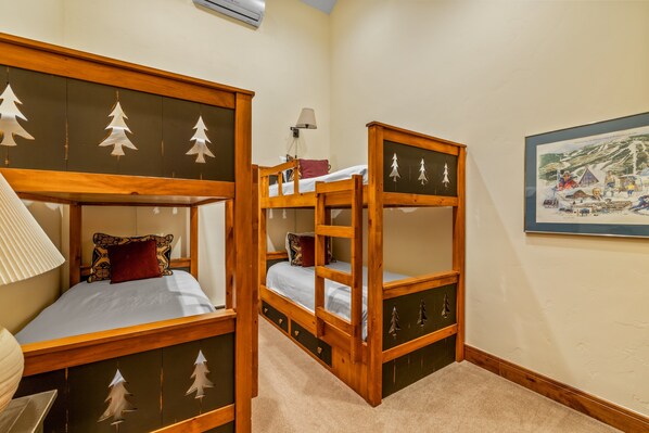 A room with bunk beds, a lamp, a framed picture, and a carpeted floor.