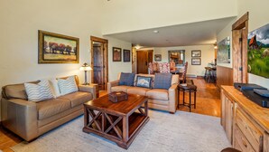A spacious living room with two sofas, a coffee table, and a dining area with chairs. - Bear Claw 614 Premium On Mountain Condo with Ski-In/Ski-Out Access! (Steamboat Springs)