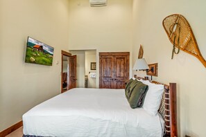 Une chambre avec un grand lit, une armoire en bois et un tableau accroché au mur.