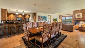 A spacious living room with a large wooden dining table, matching chairs, and a fireplace. - Bear Claw 614 Premium On Mountain Condo with Ski-In/Ski-Out Access! (Steamboat Springs)