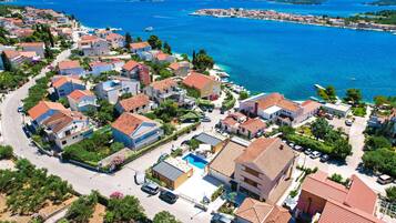 A coastal residential area with houses, a road, and a clear view of the sea.