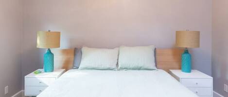 Un dormitorio con una cama, dos mesitas de noche y lámparas.