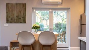 Una cocina moderna con horno empotrado, un comedor con dos sillas y un amplio ventanal con vistas al exterior.