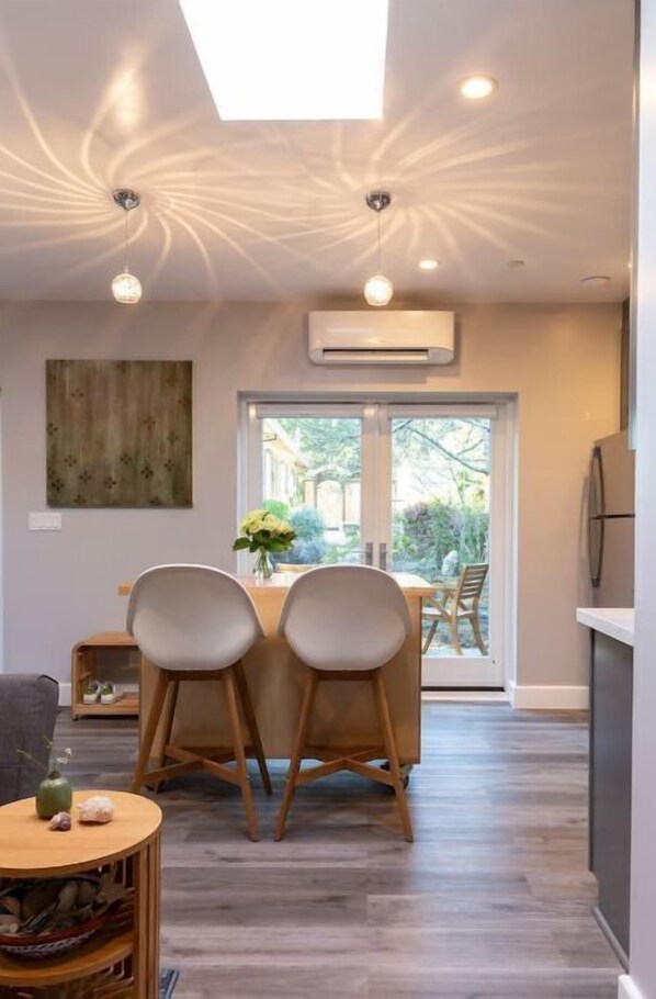 A modern kitchen with a built-in oven, a dining area with two chairs, and a large window providing a view of the outdoors.