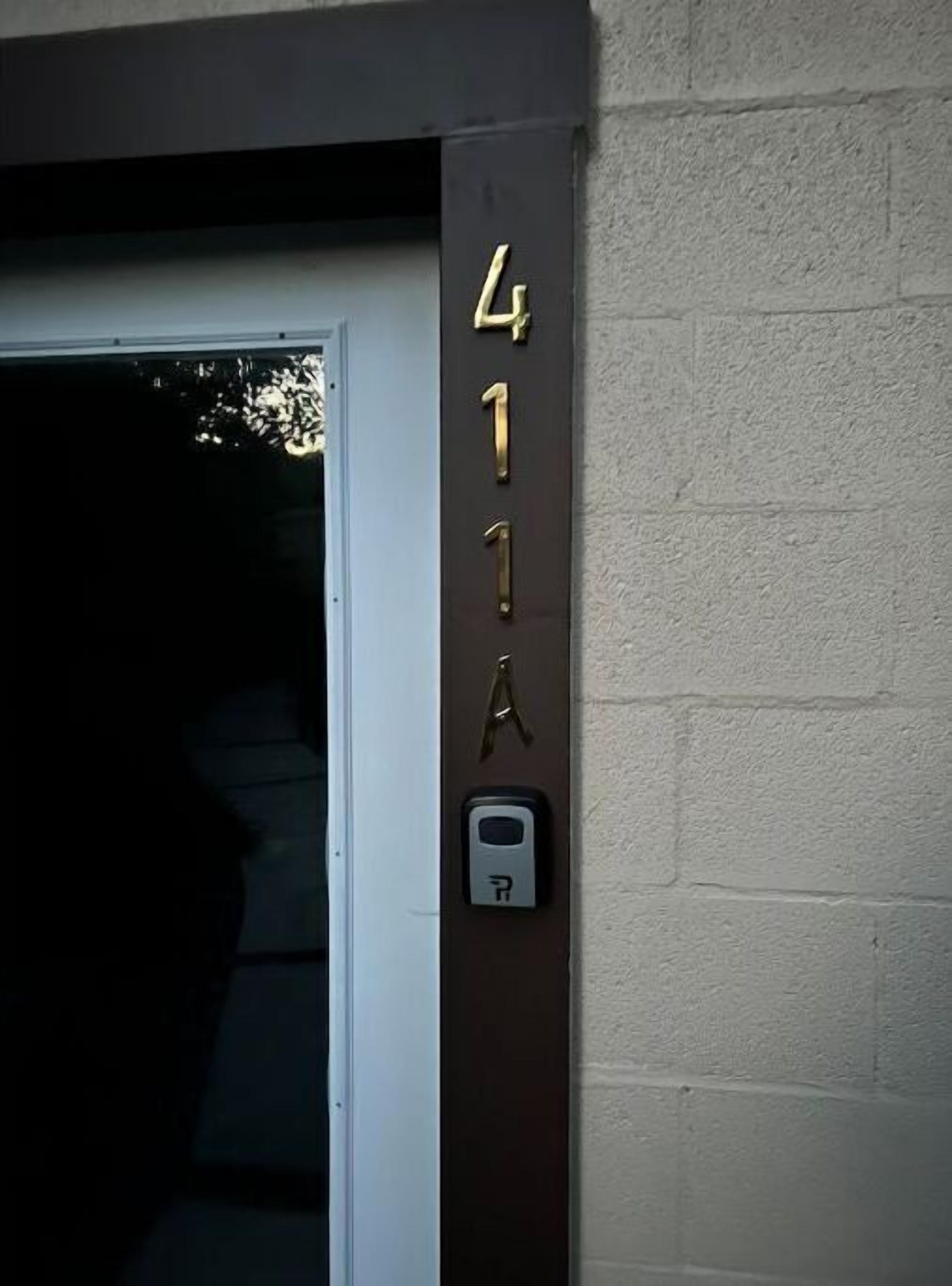 A building entrance with a door and a wall-mounted number plate displaying '411A'.