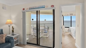 A room with a balcony, a bed, a chair, a lamp, and a cactus. - 🌴 Caprice Resort Unit #507 – Gulf Front Stunner with Full Kitchen & Balcony Views (Saint Pete Beach)