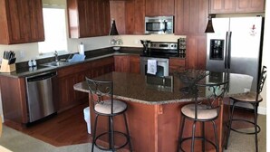 Uma cozinha moderna com armários de madeira, eletrodomésticos de aço inoxidável e uma ilha central com banquetas.