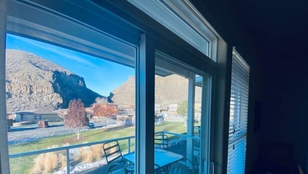 A balcony with a table and chairs, overlooking a mountainous landscape with a clear sky.