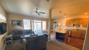 A spacious living area with a sofa, a television, and a ceiling fan.
