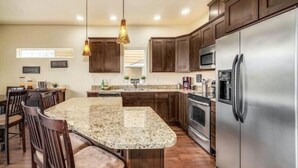 A modern kitchen with granite countertops, stainless steel appliances, and wooden cabinetry.