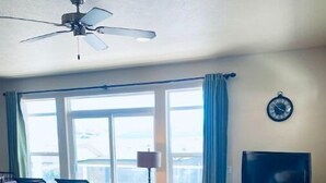 A living room with a sectional sofa, a flat-screen TV, a ceiling fan, and large windows. - D28-ATCH Garage 2 Decks/Patio Sunserra Gorge AMP (Quincy)