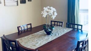 A dining area with a wooden table, six chairs, and a vase with white flowers. There are three framed pictures on the wall. - D28-ATCH Garage 2 Decks/Patio Sunserra Gorge AMP (Quincy)