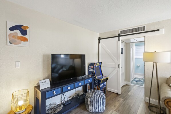 A living room with a TV, gaming console, and a sofa.