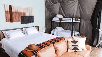 Um quarto com beliche, um sofá, um cobertor estampado e um objeto decorativo na parede.
