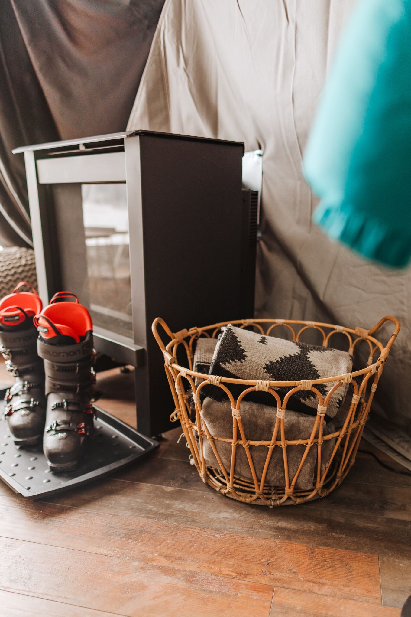 Um quarto com uma cadeira de vime, uma mesinha com botas e um armário preto.