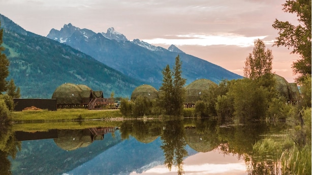 A serene lakeside scene with a cabin and a mountain backdrop. - Tammah Jackson Hole (Wilson)