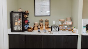 A kitchen with a refrigerator, jars, a toaster, and various food items on the counter. - Tammah Jackson Hole (Wilson)