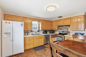 Una cocina con armarios de madera, un refrigerador, un microondas, una estufa y un lavamanos.