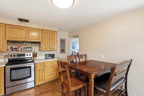 A kitchen with wooden cabinets, a stove, and a dining table with chairs.