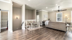 Un salon spacieux avec un grand canapé, une table à manger et des chaises, ainsi qu’un ventilateur de plafond.