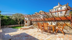 A patio with stone flooring and wooden furniture, a stone oven, and a view of a house with a balcony. - Amazing home in Icici with WiFi (Icici)