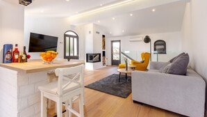 A modern living space with a kitchen area, a dining table with chairs, a sofa, and a TV mounted on the wall. - Amazing home in Icici with WiFi (Icici)