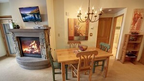 Ein Essbereich mit Kamin, einem darüber montierten Fernseher und einer Chandelüster.