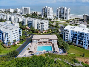 Residents enjoy stunning views of the surrounding landscape from their balconies, with a central pool area offering lounge chairs and a pavilion for relaxation and socializing.