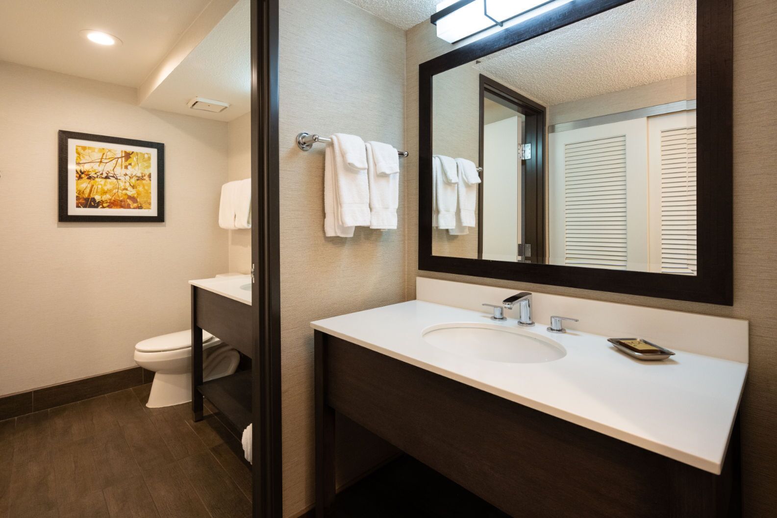 A modern bathroom with a white sink, a large mirror, and a toilet.