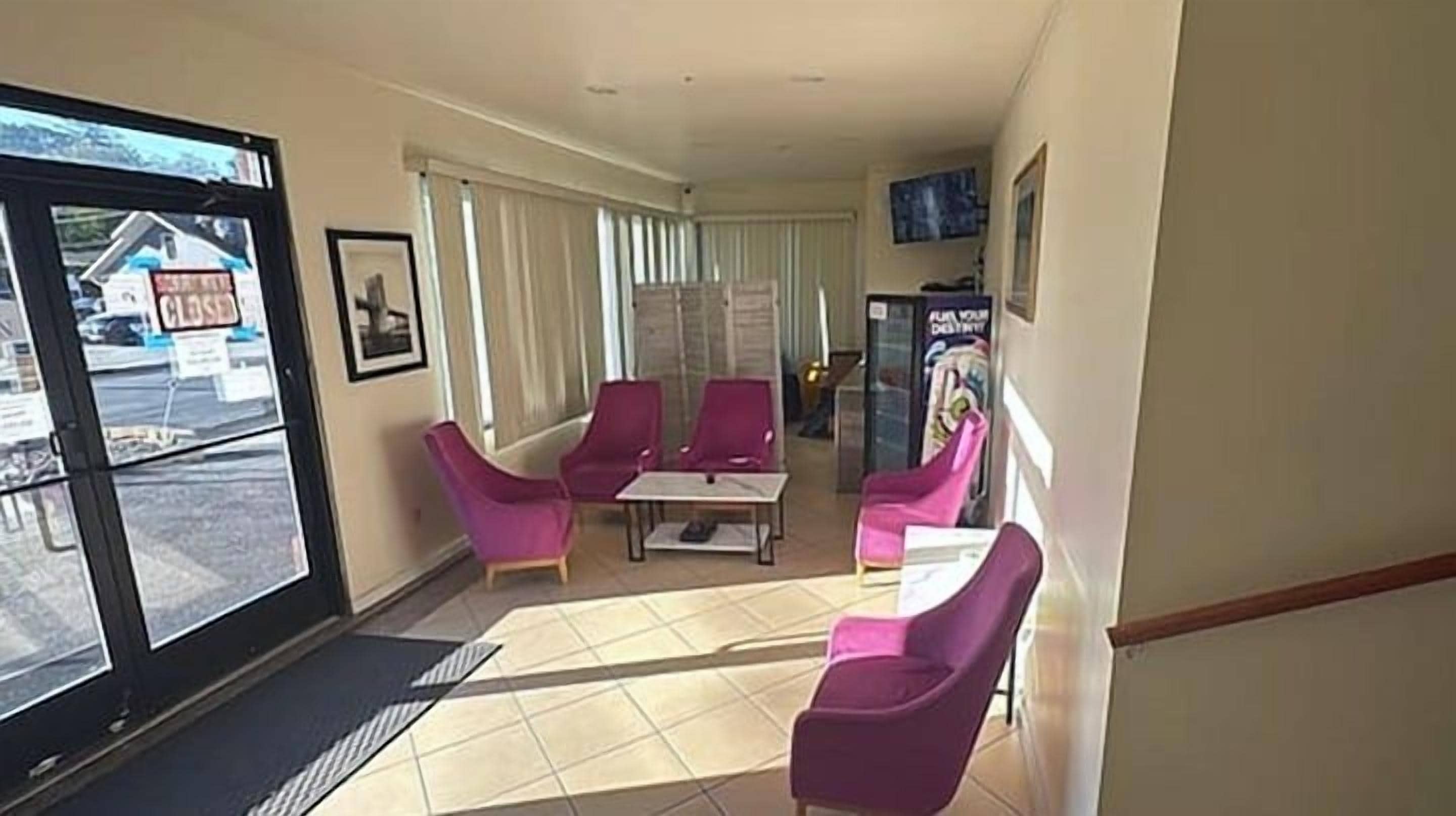 Een hotel lobby met een receptiebalie, een zithoek met stoelen en een groot raam.