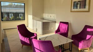 A modern kitchen with a marble countertop and a dining area with a white table and purple chairs. - The Hamlet Inn at Warwick (Warwick)