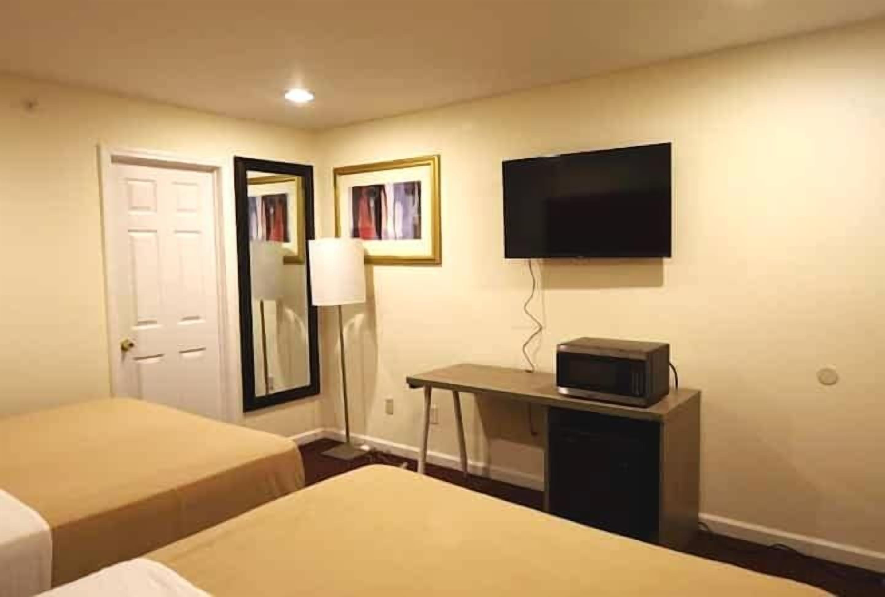 Habitació d'hotel amb dos llits, una taula de nit amb microones, televisió i mirall.