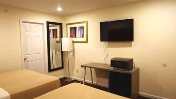 Habitació d'hotel amb dos llits, una taula de nit amb microones, televisió i mirall.
